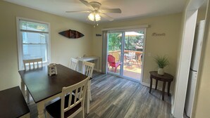 A dining area with a table, chairs, a ceiling fan, and a sliding glass door leading to an outdoor deck.