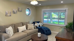 A living room with a beige sofa, a round coffee table, and a ceiling fan.