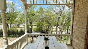 A covered outdoor dining area with a white picnic table and a brick wall. - Charming Historical 4BR Home in Central Del Rio (Del Rio)