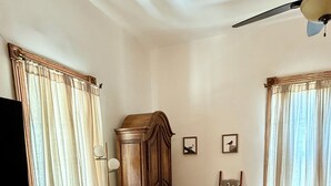 A room with wooden flooring, a large wooden cabinet, a chair, a small table, and a television on the left wall. - Charming Historical 4BR Home in Central Del Rio (Del Rio)