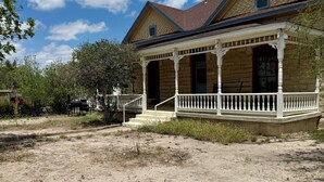 A two-story house with a porch, brick exterior, and a red roof. - Charming Historical 4BR Home in Central Del Rio (Del Rio)