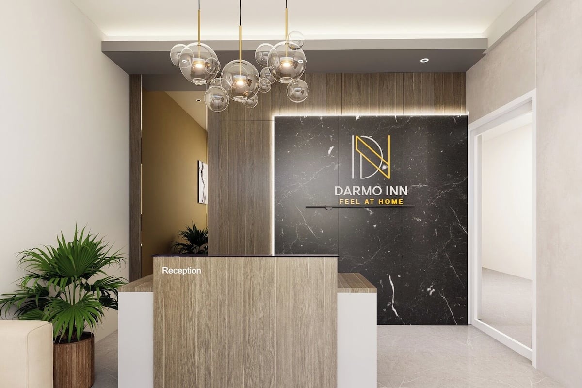 A reception desk with a modern design, a logo for Darmo Inn, and a sign that says "Feel at Home".