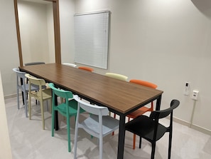 Una sala de conferencias con una mesa de madera y sillas de colores.