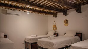 Een hotelkamer met twee enkele bedden, houten hoofdborden, een hangende hoed en een airconditioning.