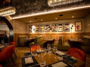A restaurant with multiple dining tables, chairs, and framed artwork on the walls. - King Room at a  Hotel (Elizabeth)