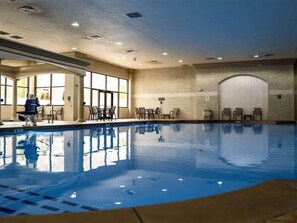 An indoor swimming pool with clear water, surrounded by seating areas and large windows. - King Room at a  Hotel (Elizabeth)