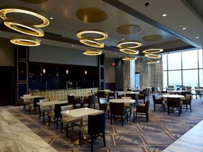 A hotel lobby with multiple seating areas, a bar, and large windows. - King Room at a  Hotel (Elizabeth)