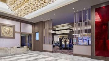 Een hotel lobby met een receptiebalie, een grote kroonluchter en een rode accentmuur.