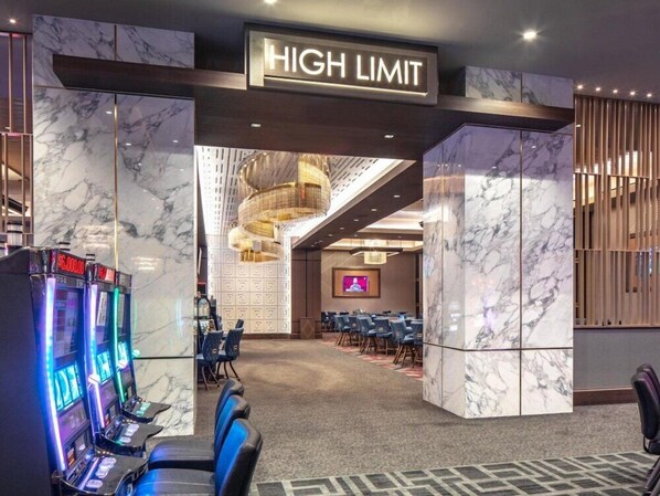 A hotel lobby with marble walls, a 'HIGH LIMIT' sign, gaming machines, and a conference room with chairs.