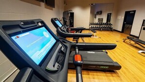 Un gimnasio con cintas de correr, una interfaz digital y mancuernas.