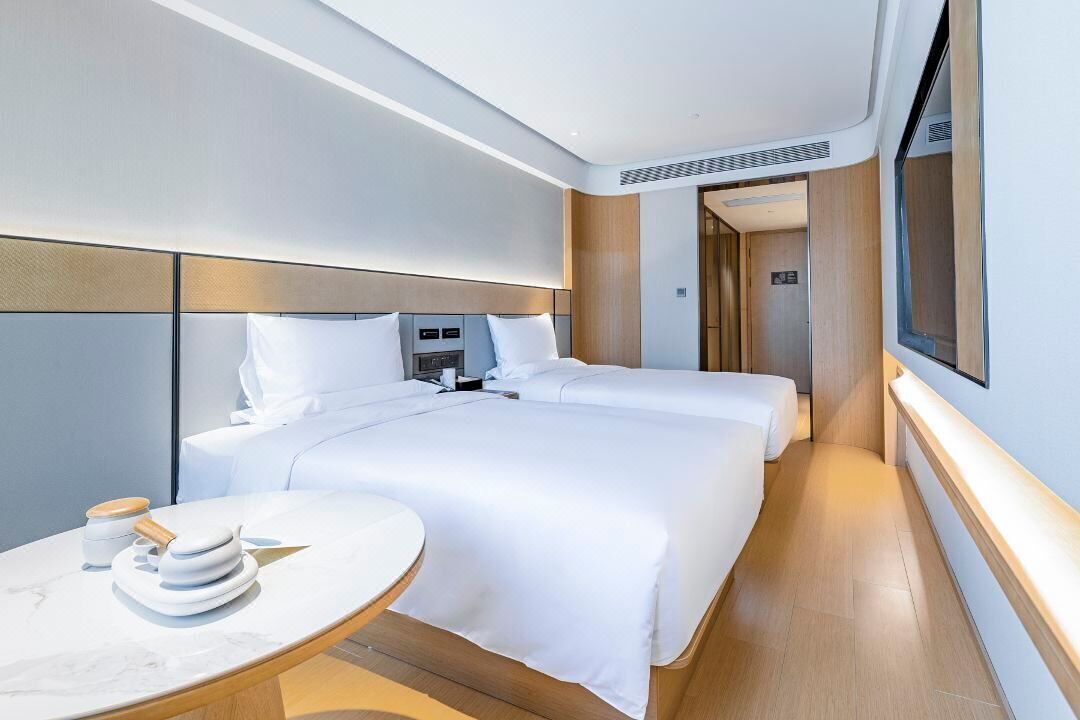 Una habitación de hotel moderna con una cama grande, mesitas de noche y un televisor.