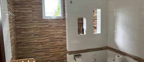 Un baño con panel de pared de madera, una ventana, un inodoro y un perchero para toallas.