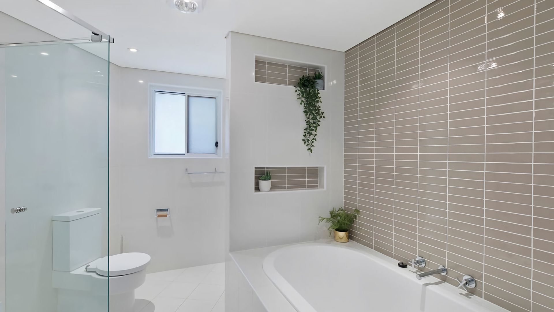 A modern bathroom with a glass shower enclosure, a toilet, a bathtub, and a window.