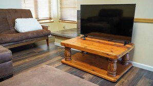 A living room with a brown sofa, a wooden coffee table, and a flat-screen TV. - Charming 2-bedroom apartment with AC in Rainier (Rainier)
