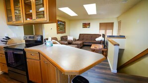 A compact kitchen with a built-in oven and a dining area with a wooden table and chairs. - Charming 2-bedroom apartment with AC in Rainier (Rainier)