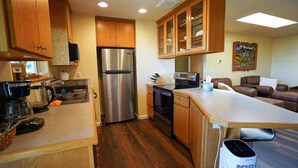 A kitchen with wooden cabinets, a stainless steel refrigerator, an oven, and a coffee maker. - Charming 2-bedroom apartment with AC in Rainier (Rainier)