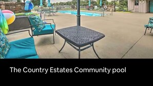 A covered outdoor area with a pool, lounge chairs, and umbrellas.