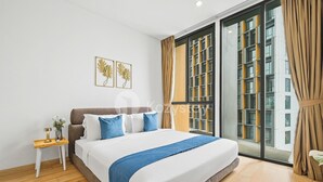 A modern bedroom with a large bed, a nightstand, and a window with curtains.