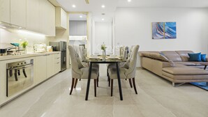 A modern kitchen with a dining area, a sofa, and a painting on the wall.