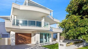 A modern two-story house with a balcony, a garage, and a well-maintained lawn. - Skywaters Retreat 2 Bedroom (The Entrance)