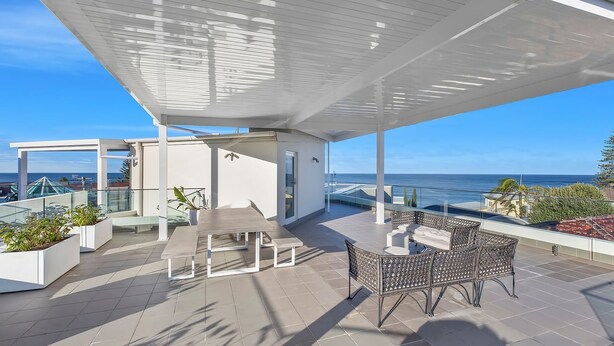 A rooftop terrace with a dining area, outdoor seating, and a view of the sea. - Skywaters Retreat 2 Bedroom (The Entrance)