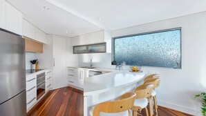 A modern kitchen with a central island, bar stools, and a large window with frost patterns. - Skywaters Retreat 2 Bedroom (The Entrance)