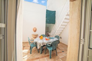 An outdoor patio with a table set for two, a chair, a decorative wall piece, and a staircase. - Rusciu Te Lu Mare Apartment with Terrace & Garden, Porto Cesareo, Italy (Porto Cesareo)