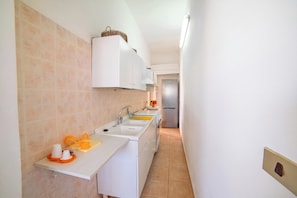A narrow kitchen with white cabinets, a stainless steel refrigerator, and a tiled backsplash. - Rusciu Te Lu Mare Apartment with Terrace & Garden, Porto Cesareo, Italy (Porto Cesareo)