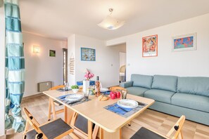 A dining area with a wooden table set for four, a sofa, and artwork on the walls.