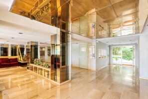A modern lobby with a glass partition, a red sofa, and a plant display.