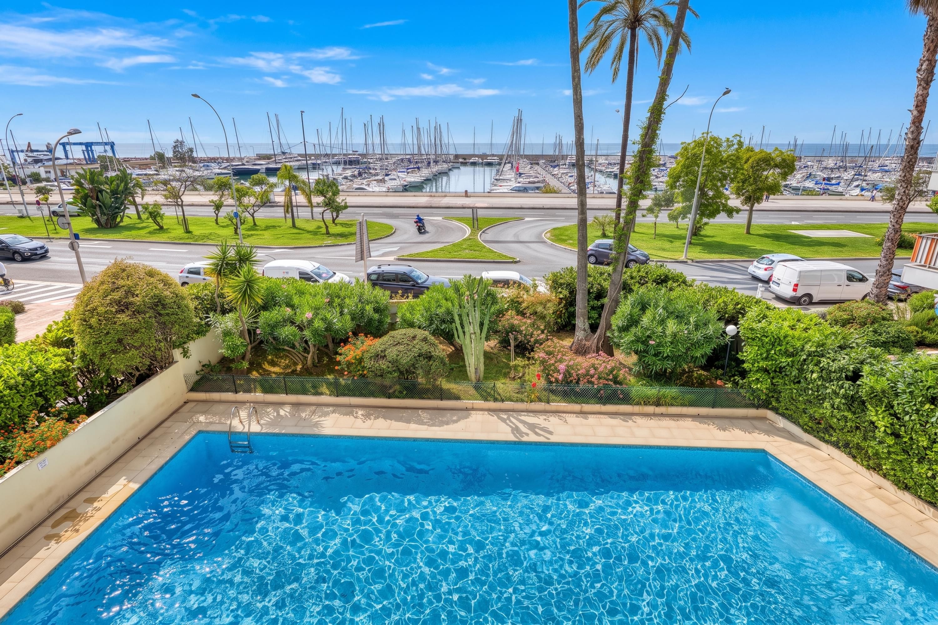 A swimming pool with a view of a marina and a road with vehicles.