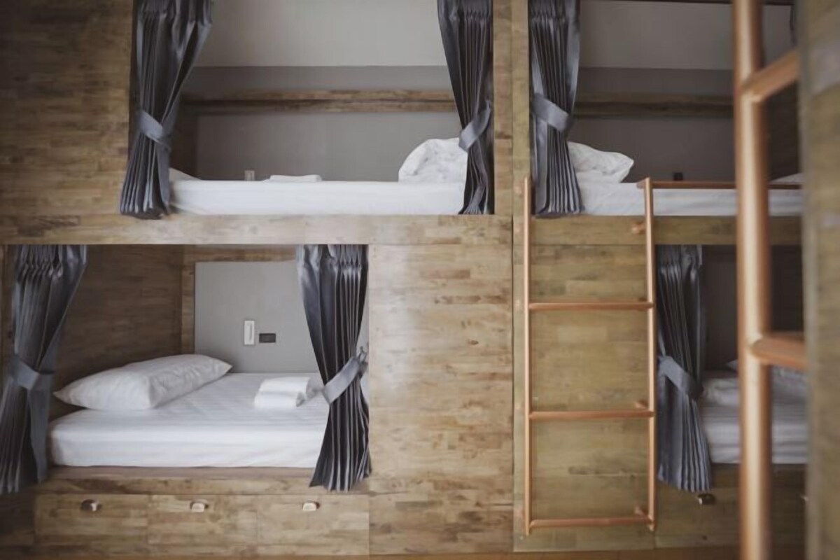 A bunk bed room with wooden walls and curtains.