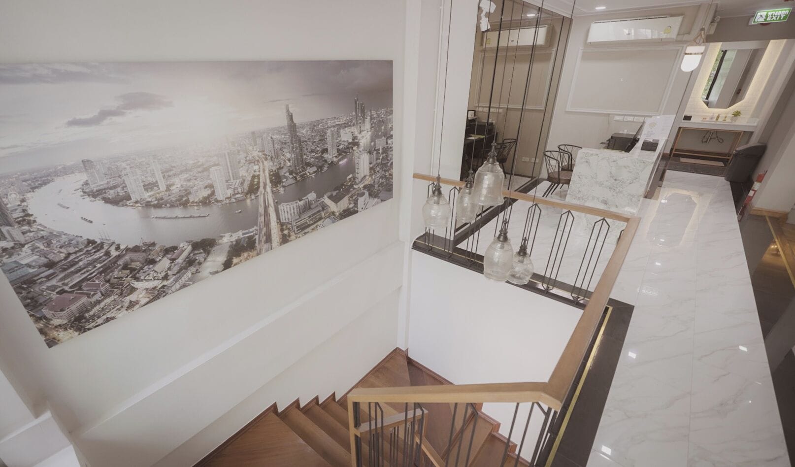 A modern interior with a staircase, a large cityscape mural, and a kitchen area with marble countertops.