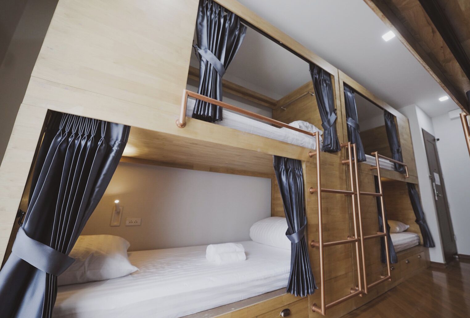A bunk bed room with curtains, a wooden ladder, and a white mattress.