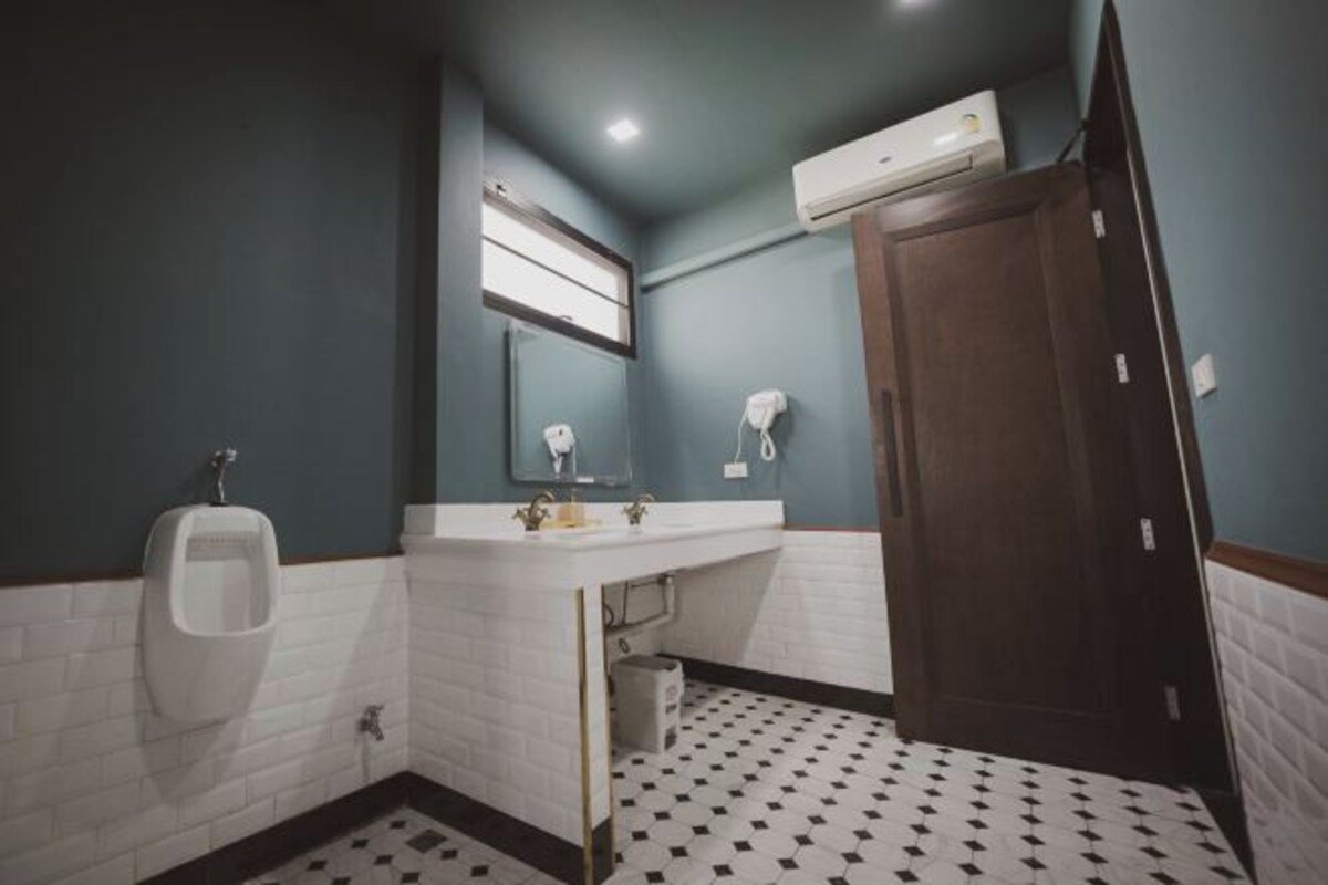 A bathroom with a urinal, sink, mirror, and a wooden door.