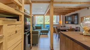 A modern kitchen with wooden beams, a built-in oven, and a dining area with a table and chairs.