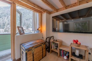 A room with a wooden chest, a television, and a window with a view of snow-covered trees. - Grand Roc B221 260m from Slopes, View, Parking & WiFi, Argentière (Chamonix), France (Argentière (Chamonix))