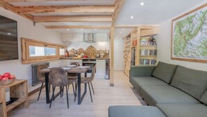 A modern kitchen with wooden beams, a dining area with a table and chairs, and a green sofa.