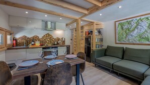 A modern kitchen with wooden beams, a dining table set with plates and glasses, and a green sofa in the living area.