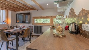 A modern kitchen with wooden beams, a large window, and a stone backsplash.