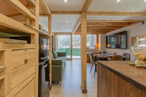 A modern kitchen with wooden beams, a built-in oven, and a dining area with a table and chairs.