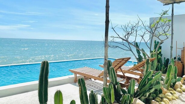 A poolside area with lounge chairs and cacti, overlooking a clear blue sea. - 3B MAISON Homestay & Villa (Mui Ne)