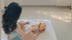A room with a bed, a window with a view of the ocean, and a dining table with food and drinks. - 3B MAISON Homestay & Villa (Mui Ne)