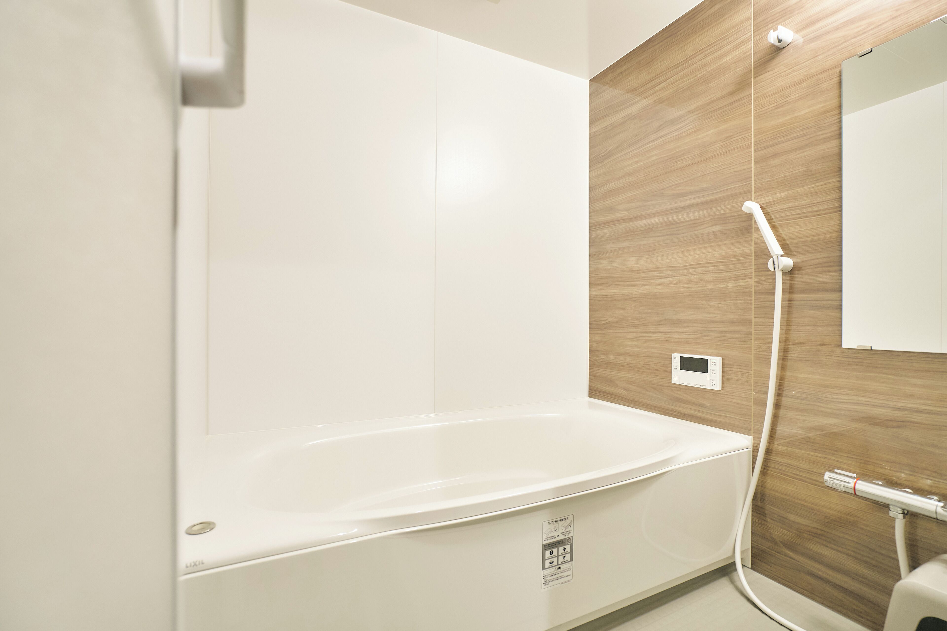 Une salle de bain moderne avec une baignoire blanche, un mur d’accent en bois et une douchette à main.