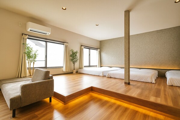 A modern hotel room with a sofa, two beds, a potted plant, and large windows. - TOMORI (Kyoto)