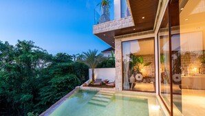 Una casa moderna amb piscina, façana de pedra i portes de vidre que donen a una zona de pati.