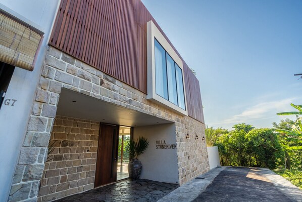 Uma villa moderna com fachada de pedra, grandes janelas e entrada acolhedora.