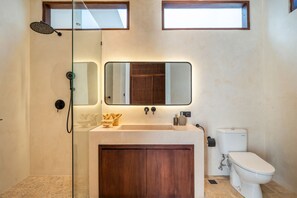 Uma casa de banho moderna com chuveiro, pia e sanita.