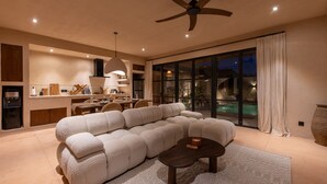 A modern living room with a sectional sofa, a coffee table, and a dining area with a table and chairs. There is a ceiling fan and a large window with curtains. - Sunset Rooftop | Private Pool | Quiet Canggu Villa (Canggu)