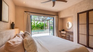 A bedroom with a large bed, a ceiling fan, a view of a swimming pool, and a bathroom with a mirror and sink. - Sunset Rooftop | Private Pool | Quiet Canggu Villa (Canggu)